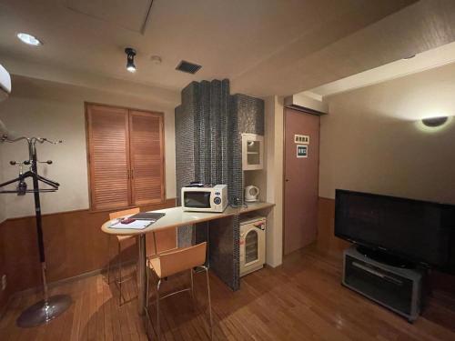 a room with a desk with a television and a table with a microwave at Hotel Luxe - Adult Only in Tokyo