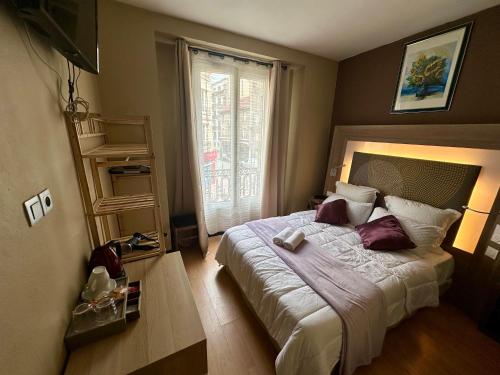 a bedroom with a large bed with a window at Hotel Victor Hugo in Clamart