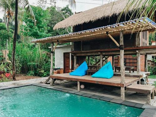 a house with blue pillows next to a swimming pool at Pondok Apsari 2 in Singaraja