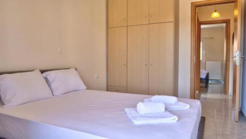 a bedroom with a white bed with towels on it at Spiridoula's Apartments Corfu in Perama