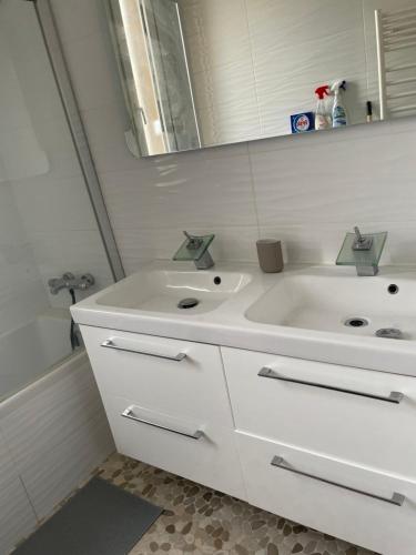 een witte badkamer met een wastafel en een spiegel bij Parisian charm flats in Levallois-Perret