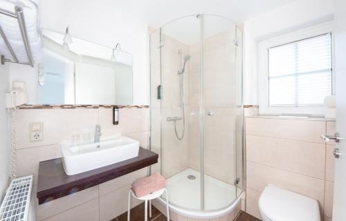 a white bathroom with a sink and a shower at Hotel & Gästehaus Im Ziegelweg KLIMATISIERT Eintrittskarten für den Europa-Park erhalten Sie garantiert über uns in Rust