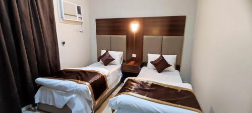 duas camas num quarto de hotel com lençóis castanhos em شقق العييري المخدومة الباحة 02 em Al Baha