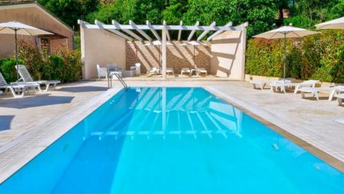 a large blue swimming pool with chairs and umbrellas at Spiridoula's Apartments Corfu in Perama