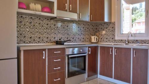 a kitchen with brown cabinets and a stove and a window at Spiridoula's Apartments Corfu in Perama