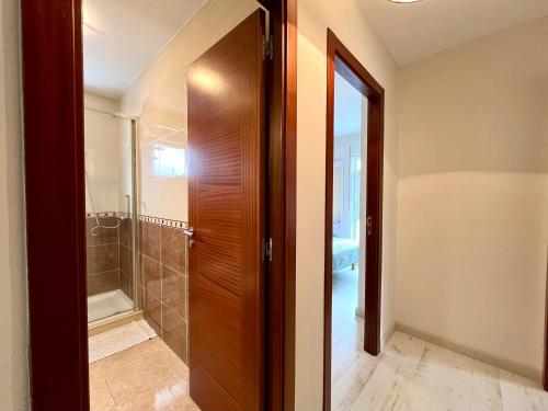 baño con ducha y puerta de madera en Castelao AP en Santiago de Compostela