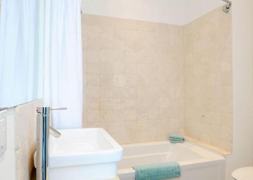a bathroom with a white tub and a white toilet at Coastal Haven: Charming Beachfront Cottage with Pool in James Cistern