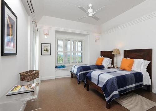 James CisternにあるCoastal Haven: Charming Beachfront Cottage with Poolのベッドルーム1室(ベッド2台、シーリングファン付)