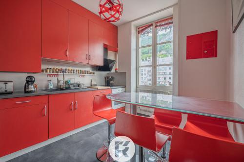 une cuisine rouge avec des armoires et des fauteuils rouges dans l'établissement R'Apparts T3 Espace Détente, à Grenoble