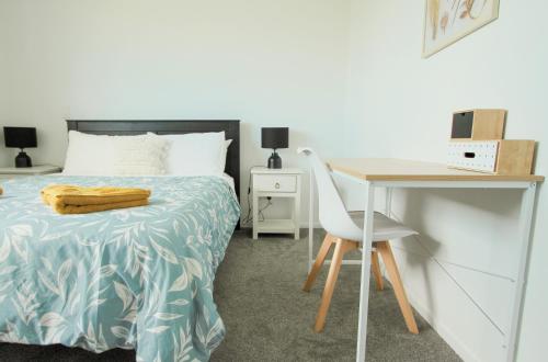 een slaapkamer met een bed en een bureau met een stoel bij New and Cosy on Salisbury Street - City Centre in Christchurch