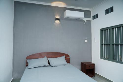 a bedroom with a bed with a wooden headboard and a window at The Chapters in Jaffna