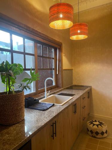 eine Küche mit einem Waschbecken, einem Fenster und zwei Lichtern in der Unterkunft Mannam apartment boho in Dahab