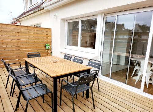 une table et des chaises en bois sur une terrasse dans l'établissement Superbe duplex 50 mètres de la plage, à Le Portel