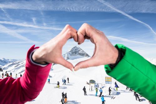 two people making a heart shape with a mountain in the background at Haus Sonnegg in Finkenberg