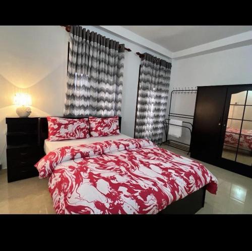 a bedroom with a red and white bed and a window at Araliya Uyana Apartments - Two Bed Room House in Ratmalana