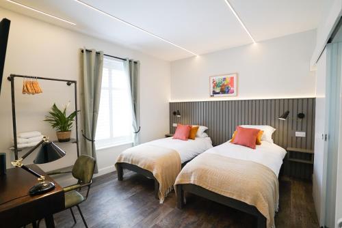 two beds in a room with a table and a desk at Sgwâr in Menai Bridge