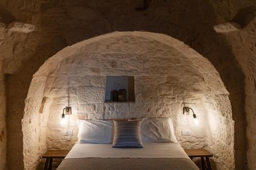 1 dormitorio con 1 cama en una pared de piedra en Trullo Jalè - Boutique Apartments, en Ostuni