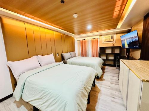 Habitación pequeña con 2 camas y TV. en Feels Like Home Condos Abreeza Place Tower 1 & 2 en Davao