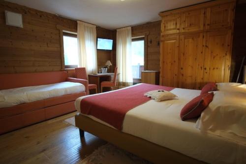 a bedroom with two beds and a chair and a table at Hotel Granta Parey in Rhêmes-Notre-Dame