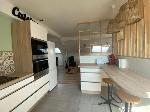 une cuisine avec des armoires blanches et un comptoir avec des tabourets dans l'établissement Chez Salomé & Théo !, à Saint-Jean-dʼArvey