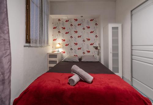 - une chambre avec un lit rouge et 2 serviettes dans l'établissement Le Lasteyras - Appartement charmant en centre ville, à Vichy