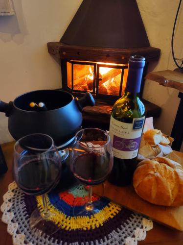Una mesa con una botella de vino y dos copas. en ACasA sua cabana com banheira Lareira Starlink, en Gonçalves