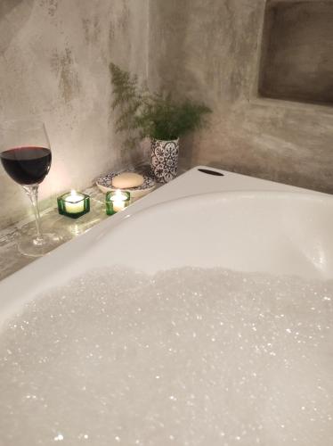 bañera con una copa de vino y un vaso de agua en ACasA sua cabana com banheira Lareira Starlink, en Gonçalves