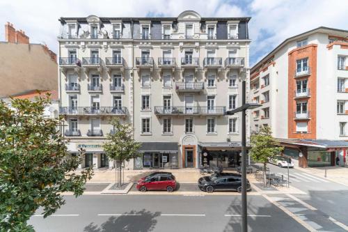 ein großes weißes Gebäude mit davor geparkt in der Unterkunft Le Lasteyras - Appartement charmant en centre ville in Vichy