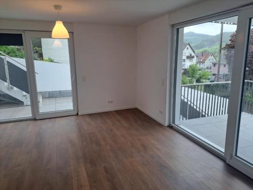 an empty living room with large glass doors and wood floors at Laura's Wohnung in Rudersberg