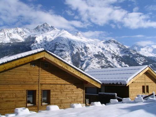 ein Blockhaus mit schneebedeckten Bergen im Hintergrund in der Unterkunft 1 2 cottage that will be perfect for families with children in La Norma