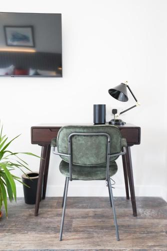 a desk with a green chair and a lamp at Sgwâr in Menai Bridge