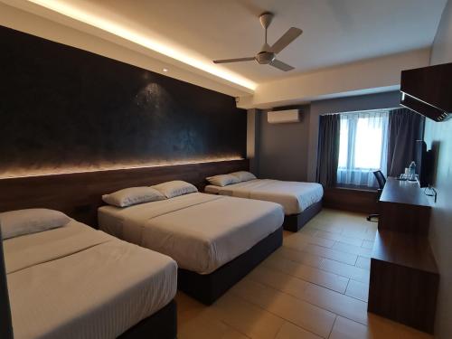 a hotel room with two beds and a ceiling fan at Lumut Hotel in Lumut