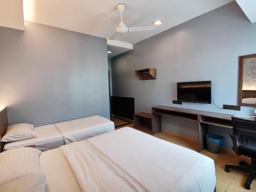 um quarto com 2 camas e uma secretária com uma televisão em Lumut Hotel em Lumut