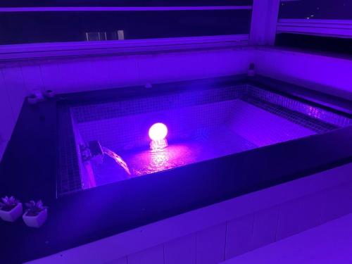 a small candle in a bath tub with purple lighting at SuiteFrattini Private Spa Rooftop in Rome