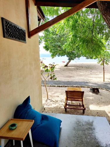 a room with a bed and a table and a beach at Beach House Penida in Nusa Penida
