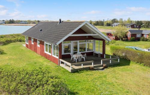 a small red house with a deck and a table at Beach Front Home In Børkop With Wifi in Børkop