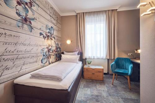 シュタルンベルクにあるHotel Starnberger Seeのベッド1台と青い椅子が備わる小さな客室です。
