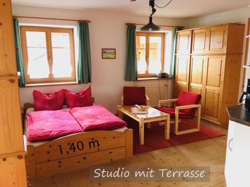 a bedroom with a bed with red pillows and a table at Ferienwohnungen Bernie Schmid in Sonthofen