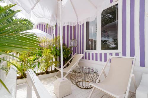 a porch with two chairs and an umbrella at Ria Uluwatu, Tropical Chic Hotel in Uluwatu