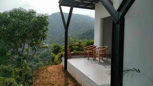 a balcony with two chairs and a view of the mountains at Mist View Resort Wayanad in Wayanad
