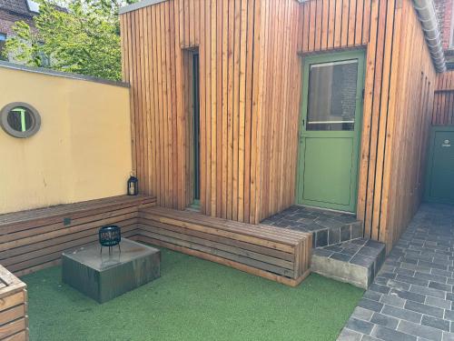un edificio de madera con una puerta verde y un patio en Victorias House Suite, en Lille