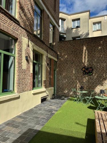 un patio de un edificio de ladrillo con césped verde en Victorias House Suite, en Lille