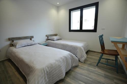 two beds in a room with a desk and a window at Le Bleu Panaché in Sfax
