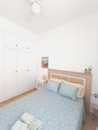 a white bedroom with a blue bed and white cabinets at Apartamento Cabo de Palos - La Manga con Aire Acondicionado in Cartagena