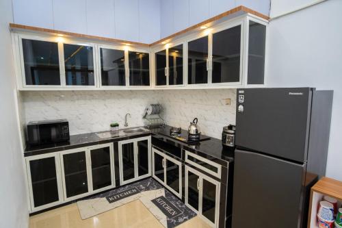 a kitchen with a black refrigerator and white cabinets at Ranya Homestay in Purwokerto