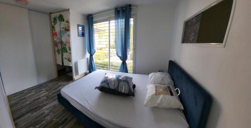 Bett in einem Zimmer mit Fenster in der Unterkunft Pierres de Jade Maison de vacances en residence avec piscine in Saint-Cyprien
