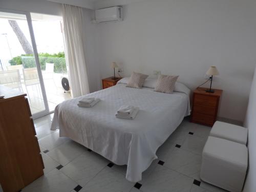 a white bedroom with a bed and a balcony at CAN VIDAL DES PORT in Port de Pollensa
