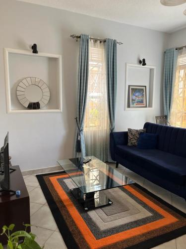a living room with a blue couch and a glass table at Vero Homes in Buwate