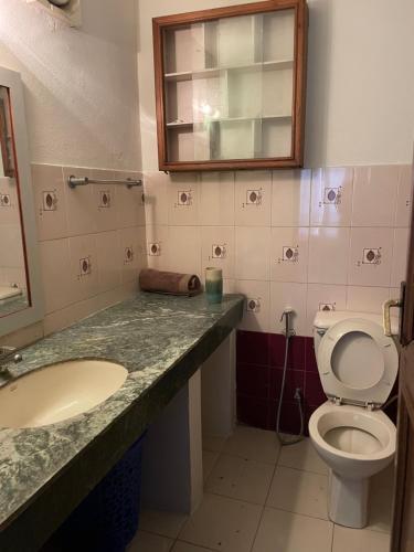 a bathroom with a toilet and a sink and a mirror at Kasaa Home in Pātan