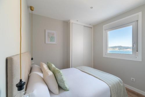 ein weißes Schlafzimmer mit einem Bett und einem Fenster in der Unterkunft El Atico de la Ria in Vigo
